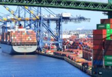 A cargo ship loaded with colorful containers docked at a busy shipping port