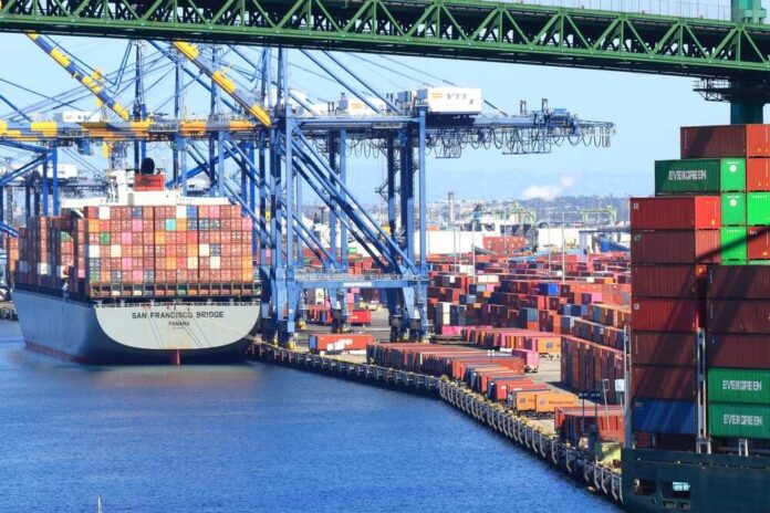 A cargo ship loaded with colorful containers docked at a busy shipping port