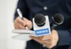 A journalist holding a notebook and microphones labeled 'NEWS'