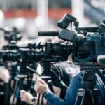 Row of cameras set up for a press event