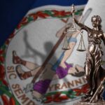 Bronze statue of Lady Justice in front of the Virginia state flag