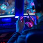 Person playing video games with a controller in a dimly lit room