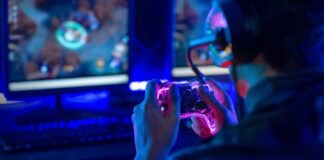Person playing video games with a controller in a dimly lit room