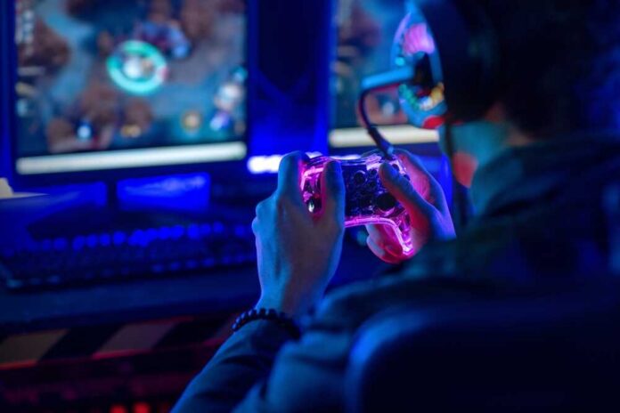 Person playing video games with a controller in a dimly lit room