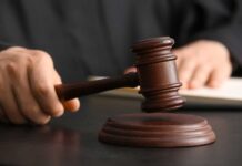 A judge's hand holding a gavel above a wooden block