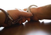 Husband Arrested: Woman’s Disappearance Sparks Federal Probe Close-up of a handcuff being secured on a wrist