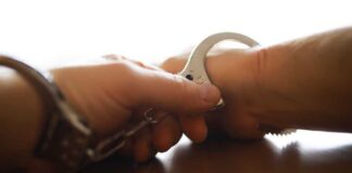 Close-up of a handcuff being secured on a wrist