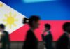 Silhouettes of people walking in front of the Philippine flag