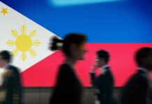 Silhouettes of people walking in front of the Philippine flag