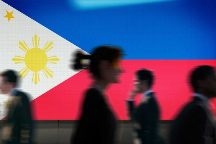 Silhouettes of people walking in front of the Philippine flag