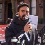 Man speaking into a microphone at a protest for senior justice