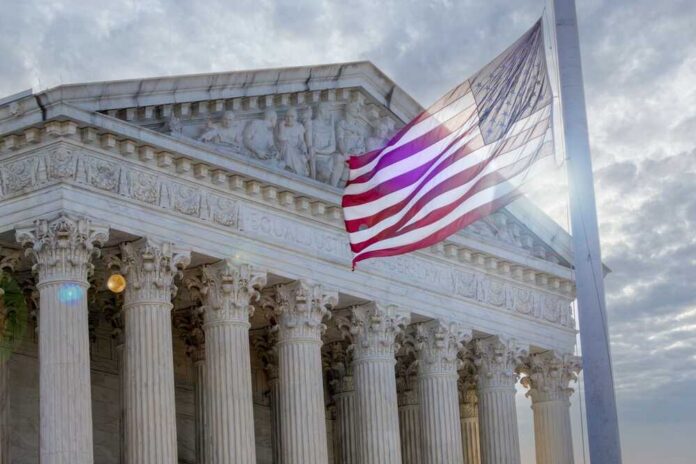 shutterstock_2671786049.jpg The Supreme Court building with an American flag waving in front