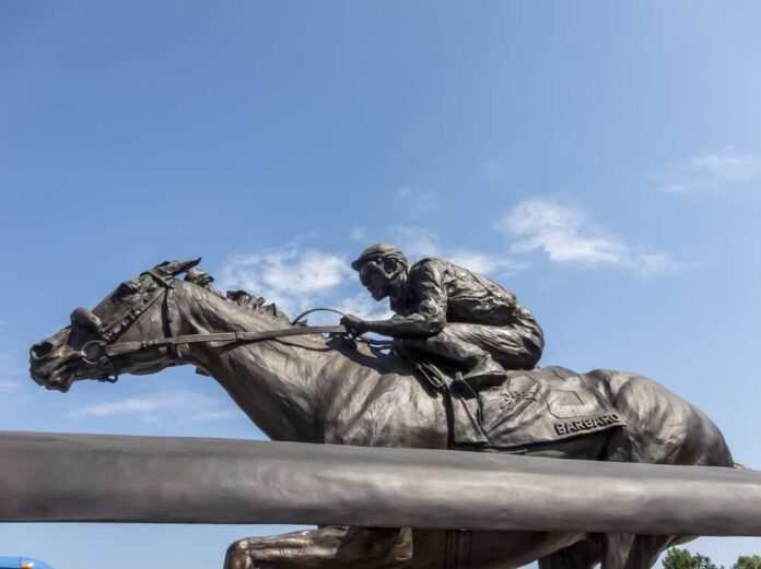 Bronze statue of a jockey riding a horse named Barbaro against a blue sky