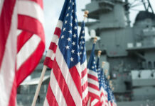 Row of American flags in front of a naval ship