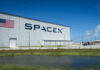 SpaceX and Wall Street: Dangerous Political Game? SpaceX building with American flag sky background