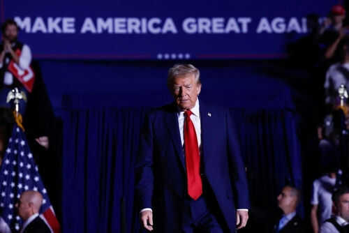 Person in red tie at rally under blue banner