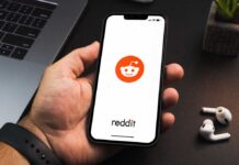 Hand holding smartphone displaying Reddit app logo