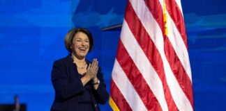 Person clapping near American flag on stage.
