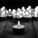Pickleball Community Mourns: Fatal Flight Disaster Single candle burning among many on wooden surface.
