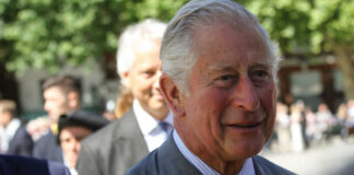 elderly man in a gray suit smiling outdoors