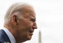 Elderly man in profile with grey hair outdoors.