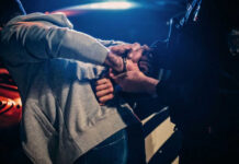Death Threat Video Triggers Rapid FBI Bust Police officer handcuffing person near a car