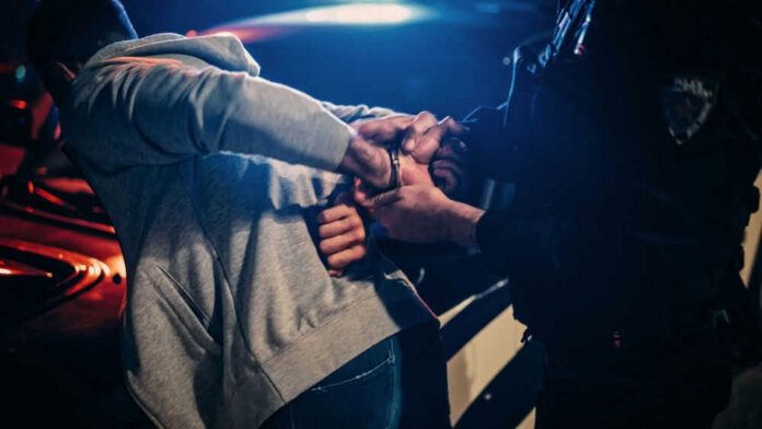 manarrestedid2232056691 Police officer handcuffing person near a car