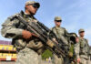 Troop Safety Compromised? Pentagon’s Risky Move Soldiers in uniform holding weapons outdoors on sunny day