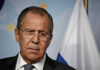 FLEE! Moscow Warns Americans Out of Kyiv NOW Man in suit with Russian flag backdrop