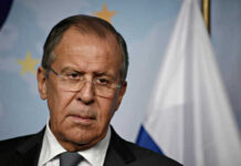 FLEE! Moscow Warns Americans Out of Kyiv NOW Man in suit with Russian flag backdrop