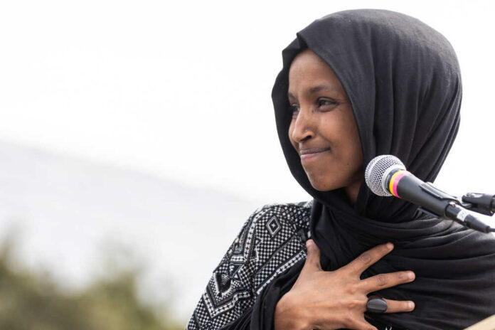 shutterstock_1369296269.jpg Ilhan Omar speaking at a microphone during an event