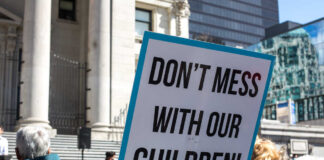 Protest sign held by a crowd in an urban square