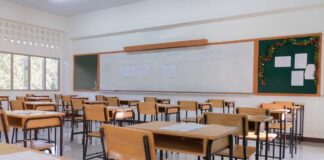 An empty classroom with wooden desks and a chalkboard