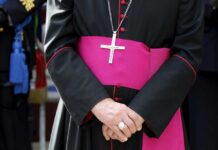 A religious figure in ceremonial attire with a cross necklace