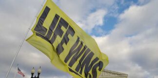 A large yellow flag with the words 'LIFE WINS' waving in front of the Supreme Court building