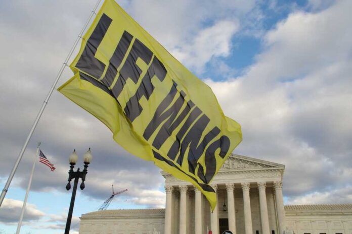A large yellow flag with the words 'LIFE WINS' waving in front of the Supreme Court building