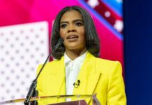 A woman in a yellow blazer speaking at a podium with a microphone