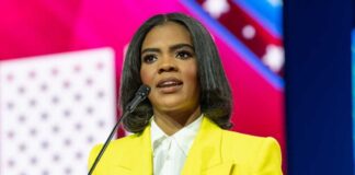 A woman in a yellow blazer speaking at a podium with a microphone