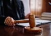 A judge's hand holding a gavel in a courtroom setting