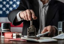 DHS Directive: Massive Green Card Process Overhaul! A person stamping passports on a desk with various stamps and documents