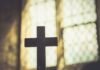 Silhouette of a wooden cross against a softly lit background