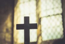 Silhouette of a wooden cross against a softly lit background