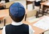 Back view of a Jewish boy wearing a kippah in a classroom setting