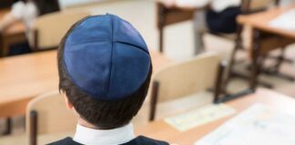 Back view of a Jewish boy wearing a kippah in a classroom setting