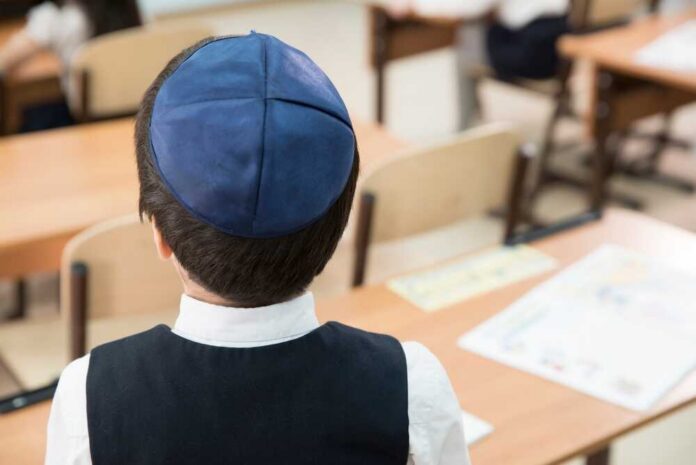 Back view of a Jewish boy wearing a kippah in a classroom setting