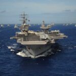 Trump’s Iran Blockade — IRGC “By the Throat” An aircraft carrier surrounded by various naval vessels in the ocean