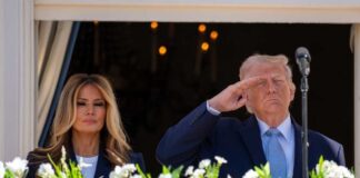 Donald Trump saluting while Melania Trump stands beside him at a public event