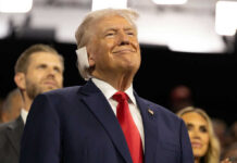 G7 Walks Tightrope on Trump Deal Smiling older man in a suit with a red tie at an indoor event