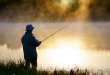 Hunting, Fishing Redefined — As Felonies A fisherman standing by a misty lake at sunrise, holding a fishing rod