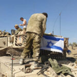 Soldiers on tank with Israeli flag in open field